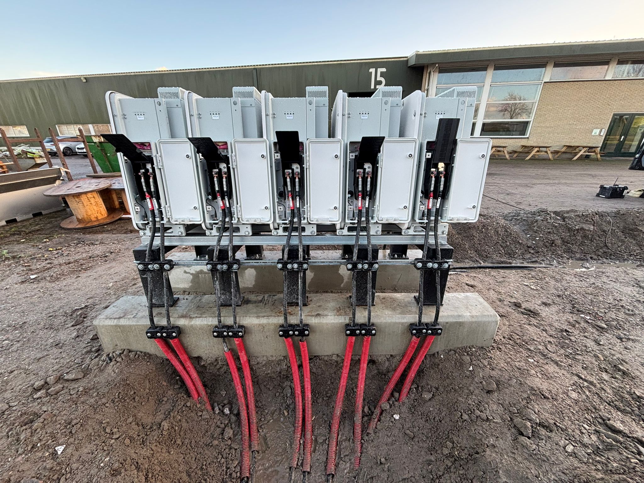 Vijf batterijmodules op een metalen onderconstructie van ROEF, met aangesloten stroomkabels.