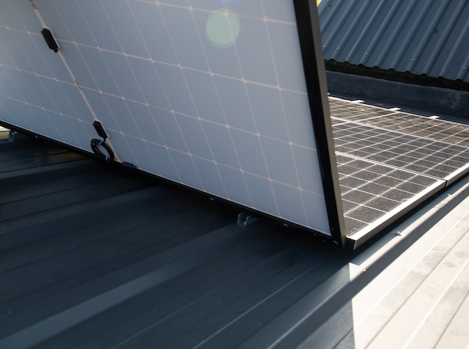Zonnepanelen gemonteerd op een schuin metalen dak.